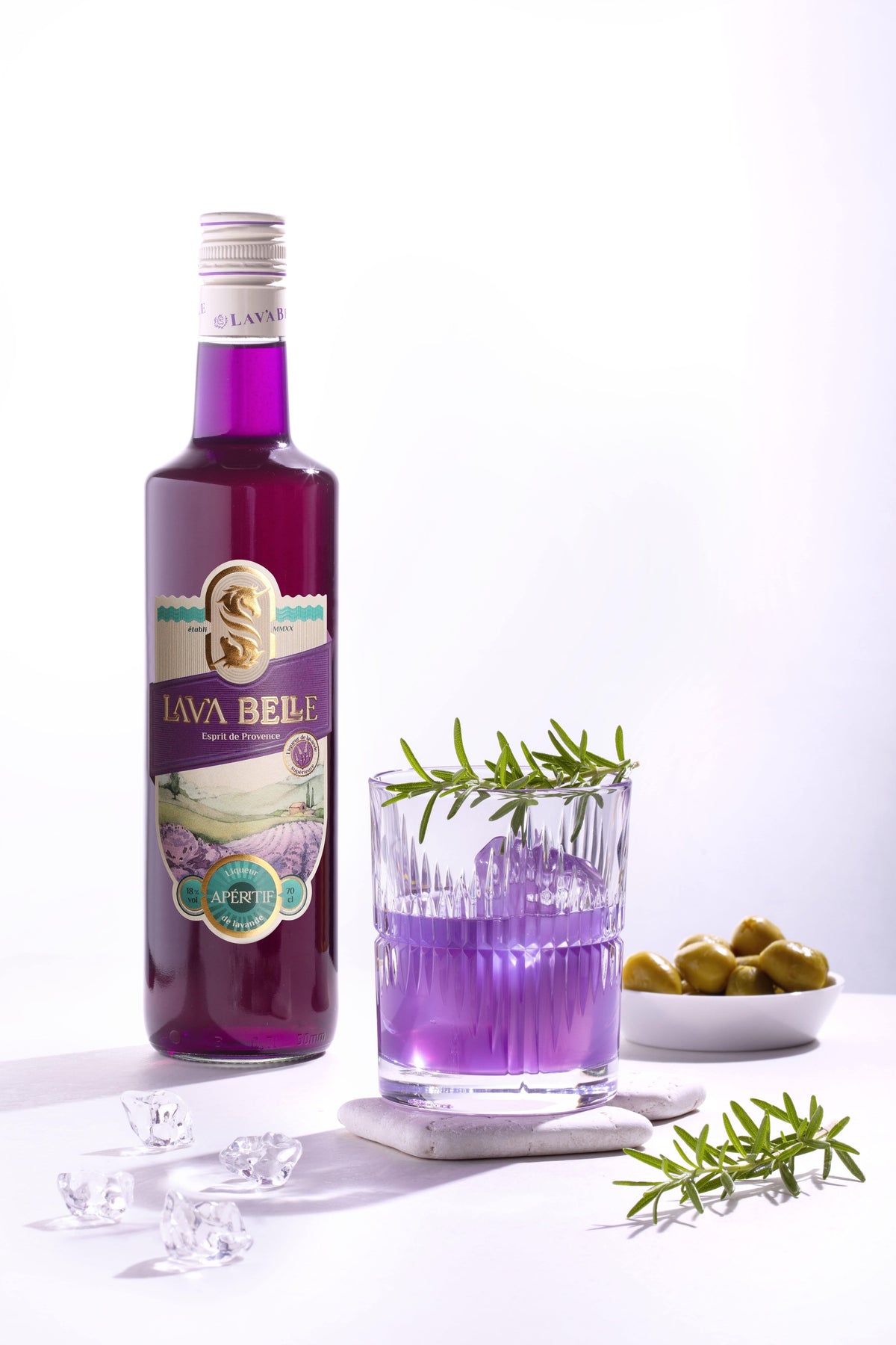 Lav'a Belle Gin Sour im Glas neben einer Flasche Lav'a Belle Apéritif