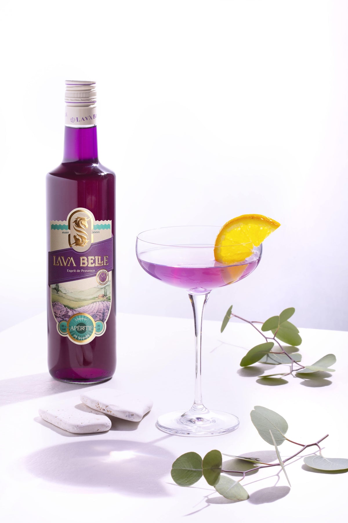 Lav'a Belle Champagner-Cocktail in einer Cocktailschale neben einer Flasche