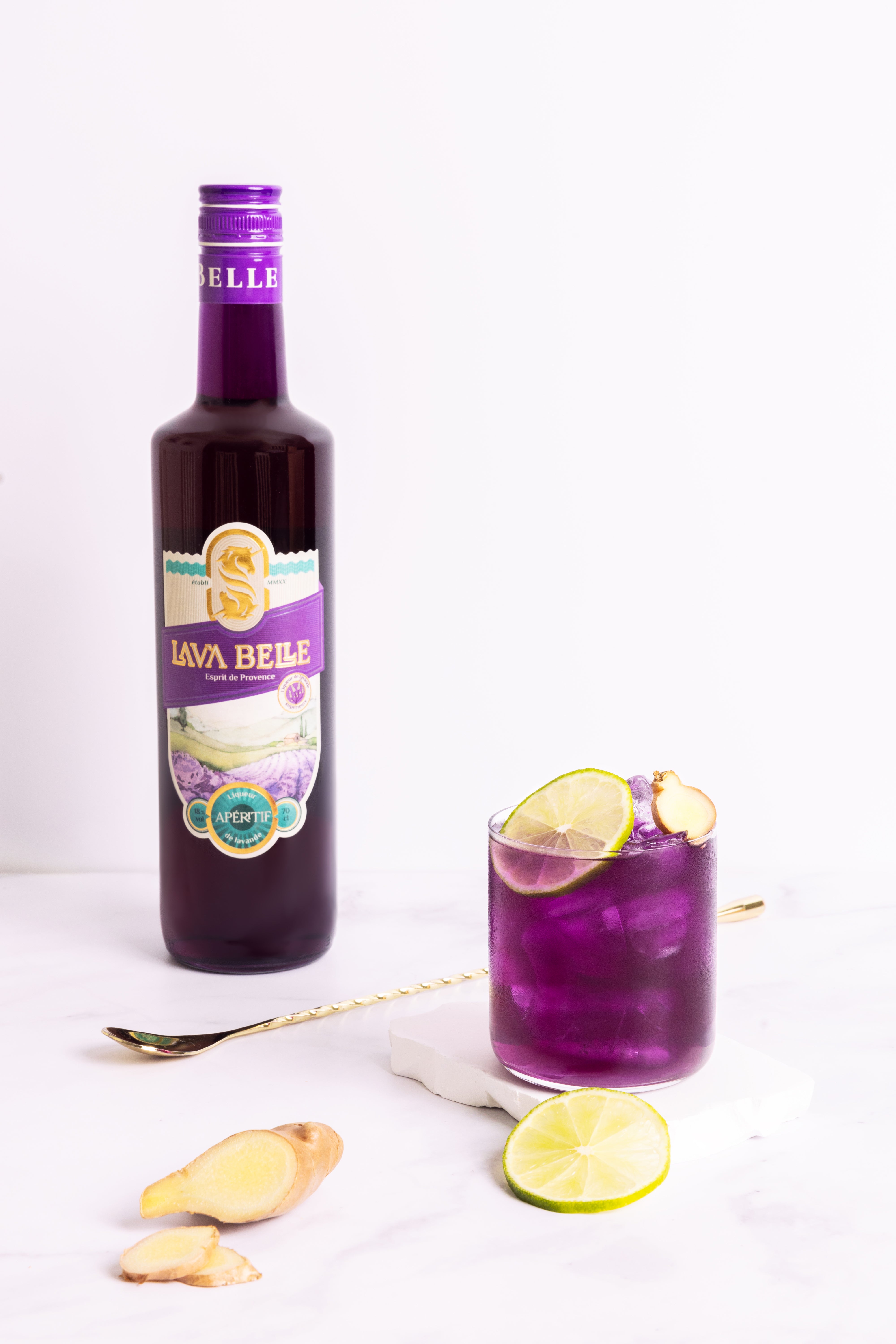 Ein Glas Nizza Mule mit Limetten- und Ingwerscheiben vor einer Flasche Lav'a Belle und Barlöffel